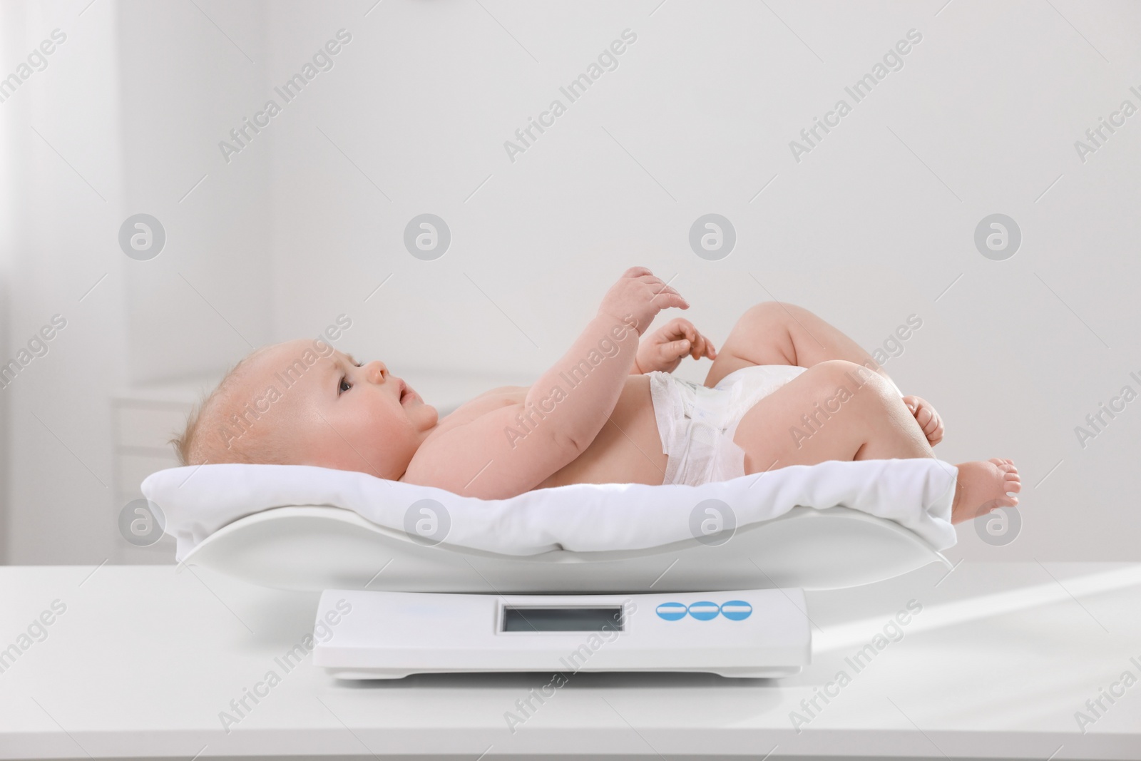 Photo of Cute little baby lying on scales in clinic