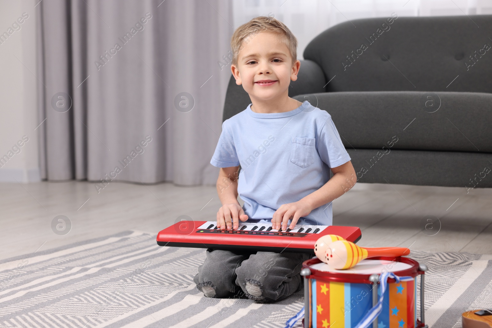 Photo of Little boy playing toy piano at home