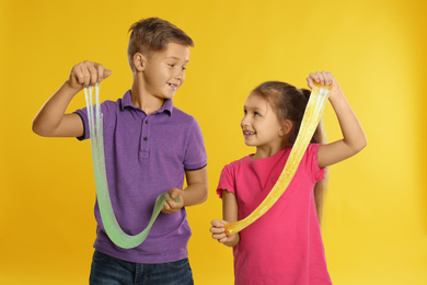 Photo of Happy children with slime on yellow background