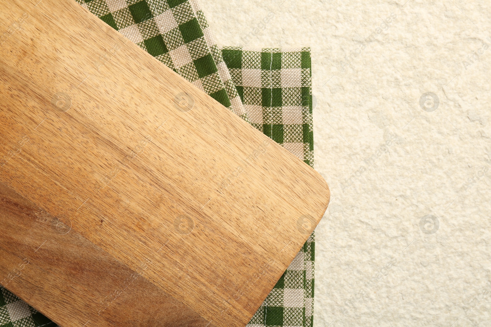 Photo of Wooden cutting board and napkin on beige table, top view. Space for text