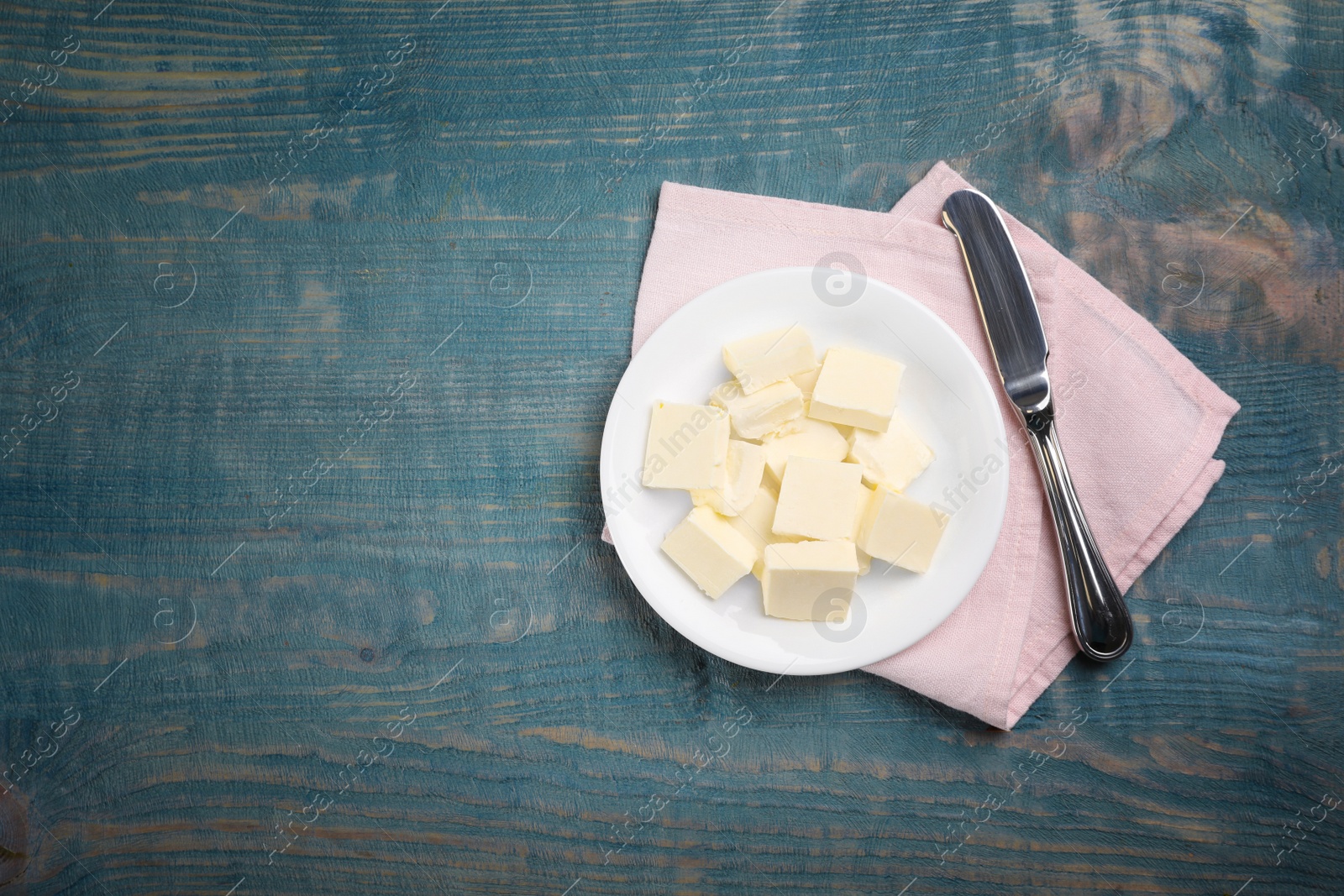 Photo of Plate with tasty fresh butter and knife on wooden background, top view