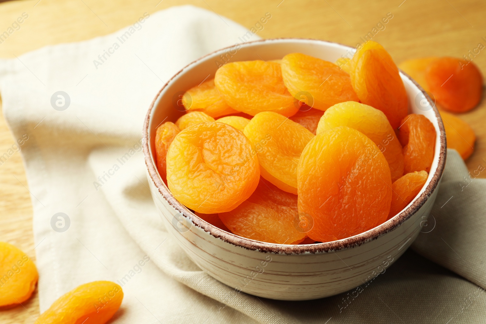 Photo of Bowl of tasty apricots on wooden table, closeup. Dried fruits