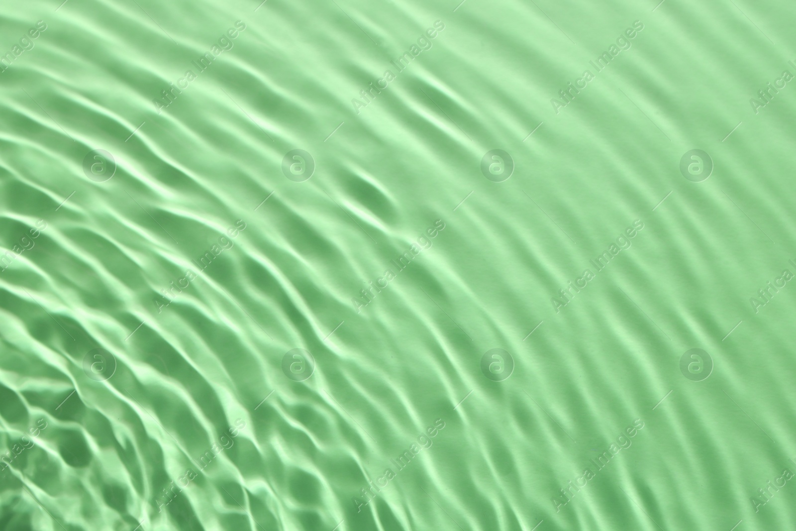 Image of Rippled surface of clear water on green background, closeup