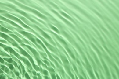 Rippled surface of clear water on green background, closeup