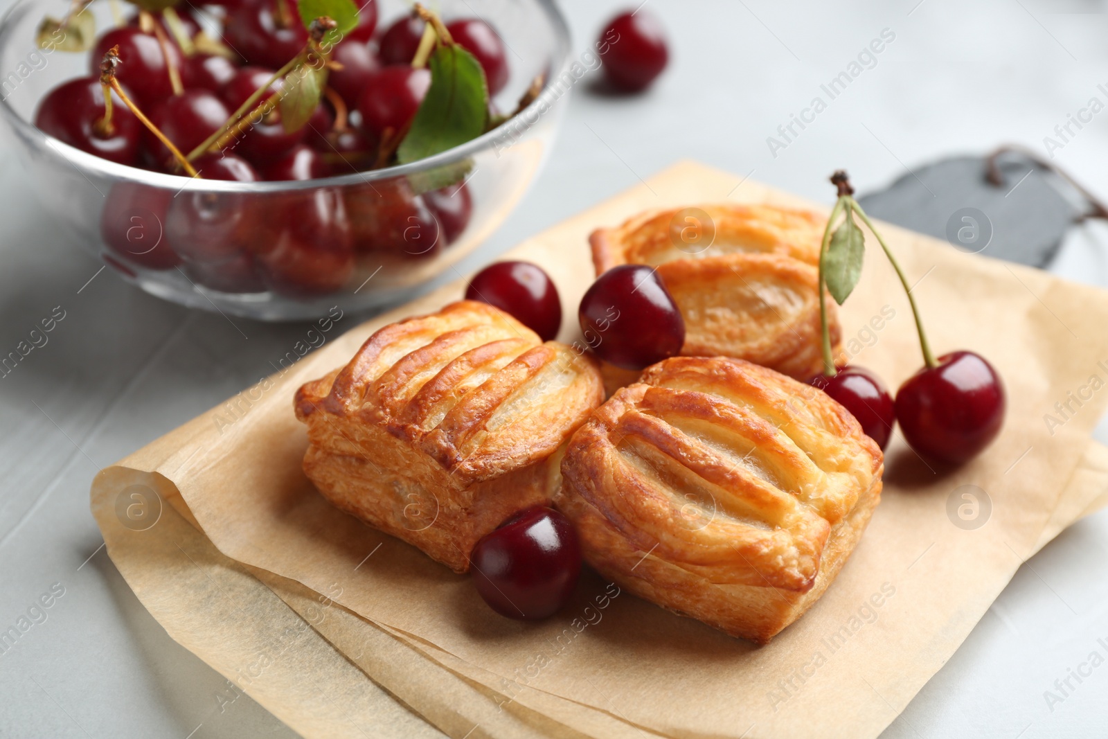 Photo of Fresh delicious puff pastry with sweet cherries served on light table