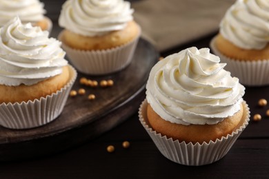 Photo of Delicious cupcakes with white cream on wooden table, closeup