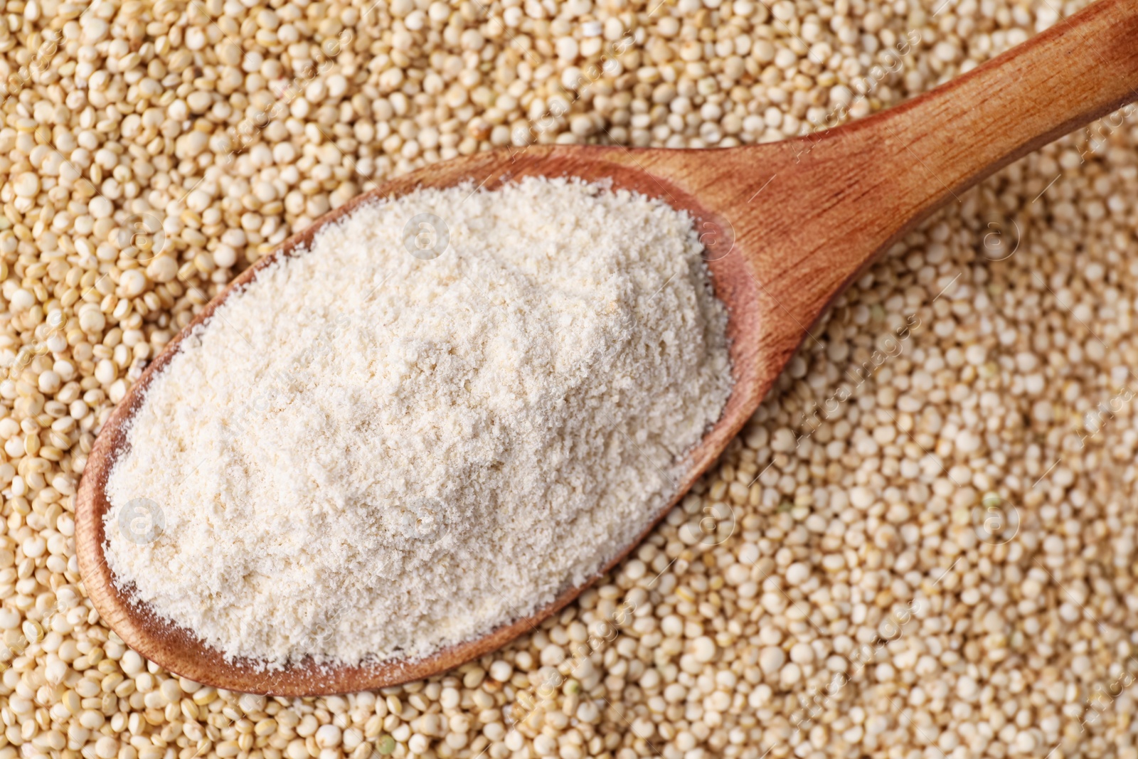 Photo of Wooden spoon with quinoa flour on seeds, closeup