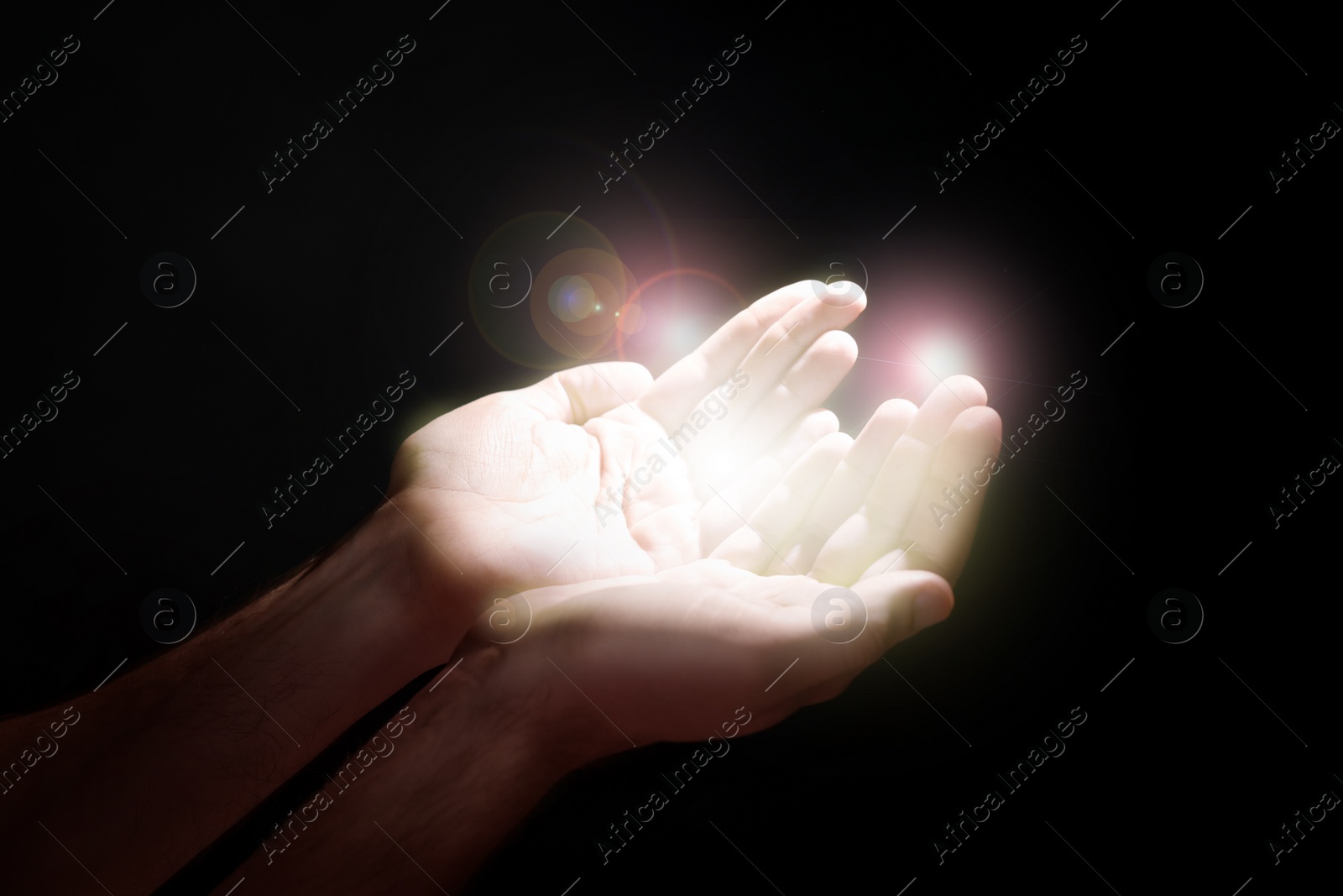 Image of Man stretching hands towards light in darkness, closeup. Praying concept