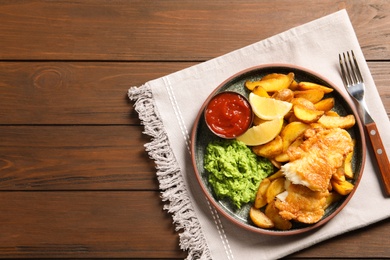 Photo of Plate with British traditional fish and potato chips on wooden background, top view. Space for text