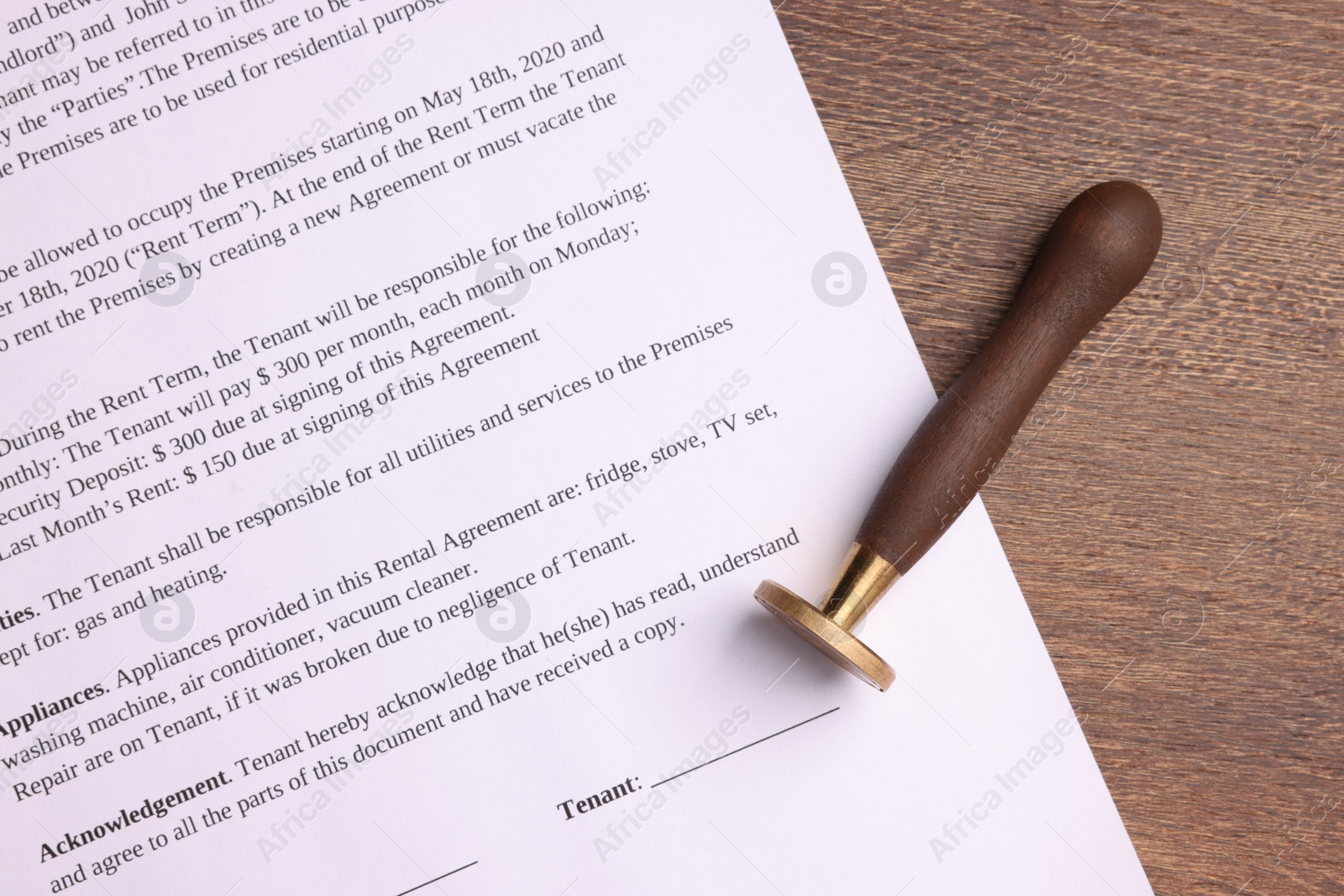 Photo of One stamp tool and document on wooden table, top view