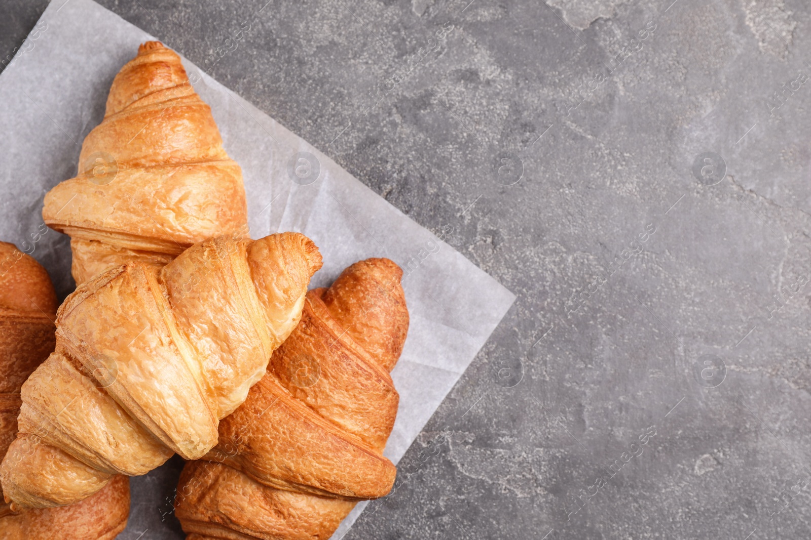 Photo of Tasty fresh croissants on grey table, flat lay. Space for text