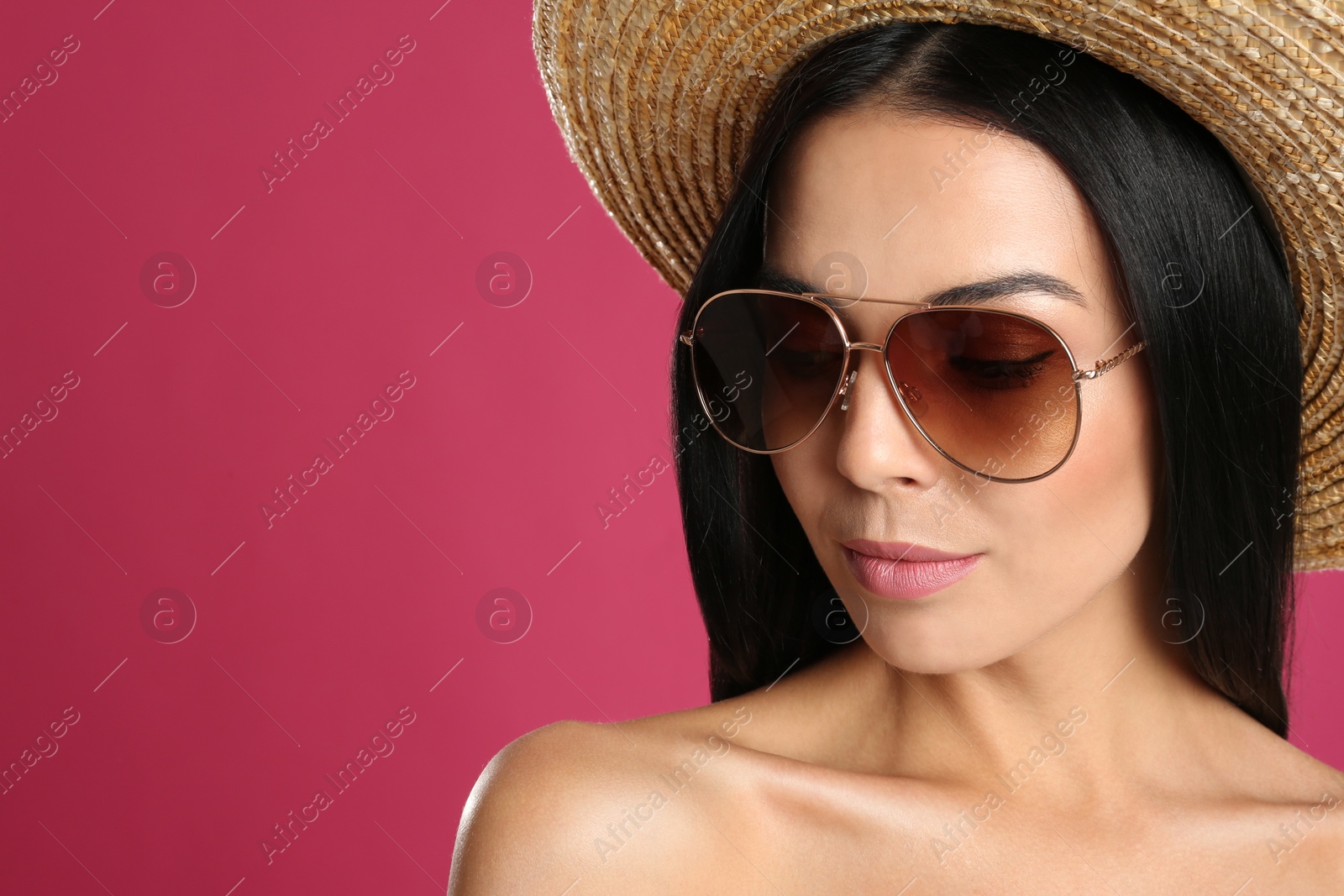 Photo of Beautiful woman wearing sunglasses on pink background, closeup. Space for text