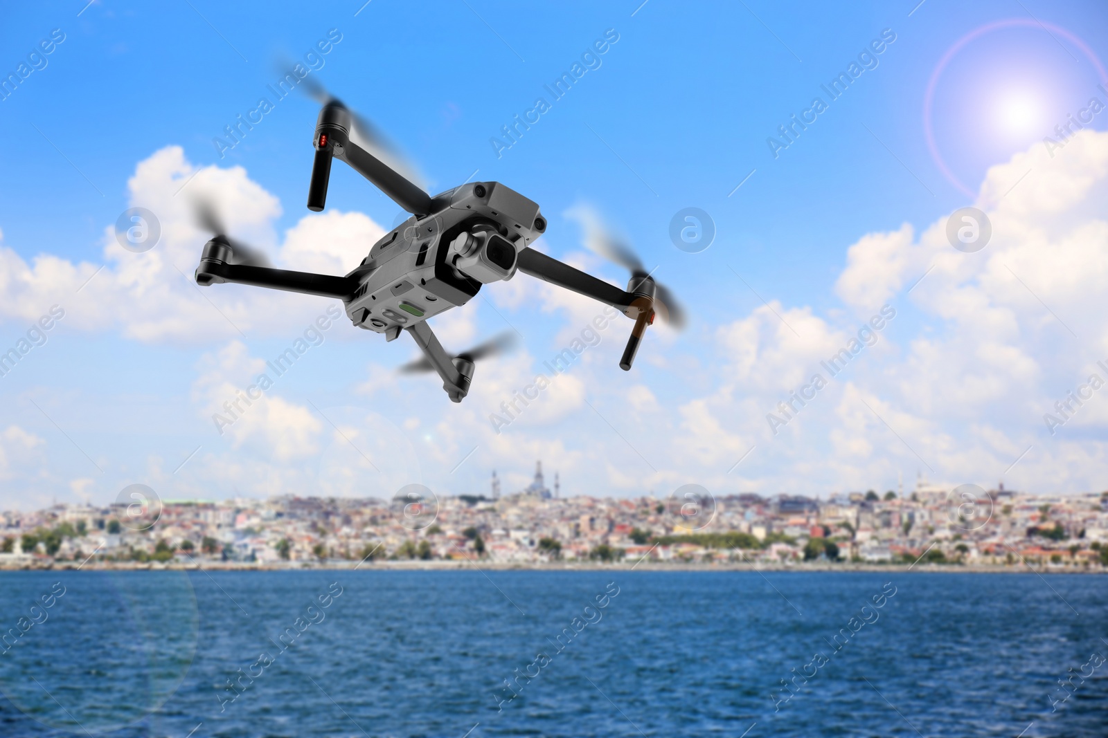 Image of Modern drone flying over sea and blurred cityscape on background. Aerial survey