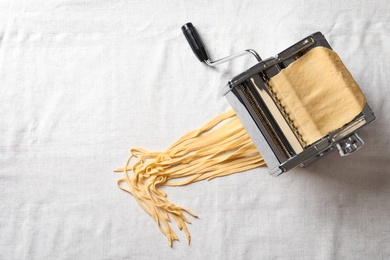 Pasta maker with wheat dough on light background, top view