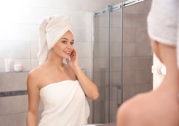 Beautiful woman with clean towels near mirror in bathroom