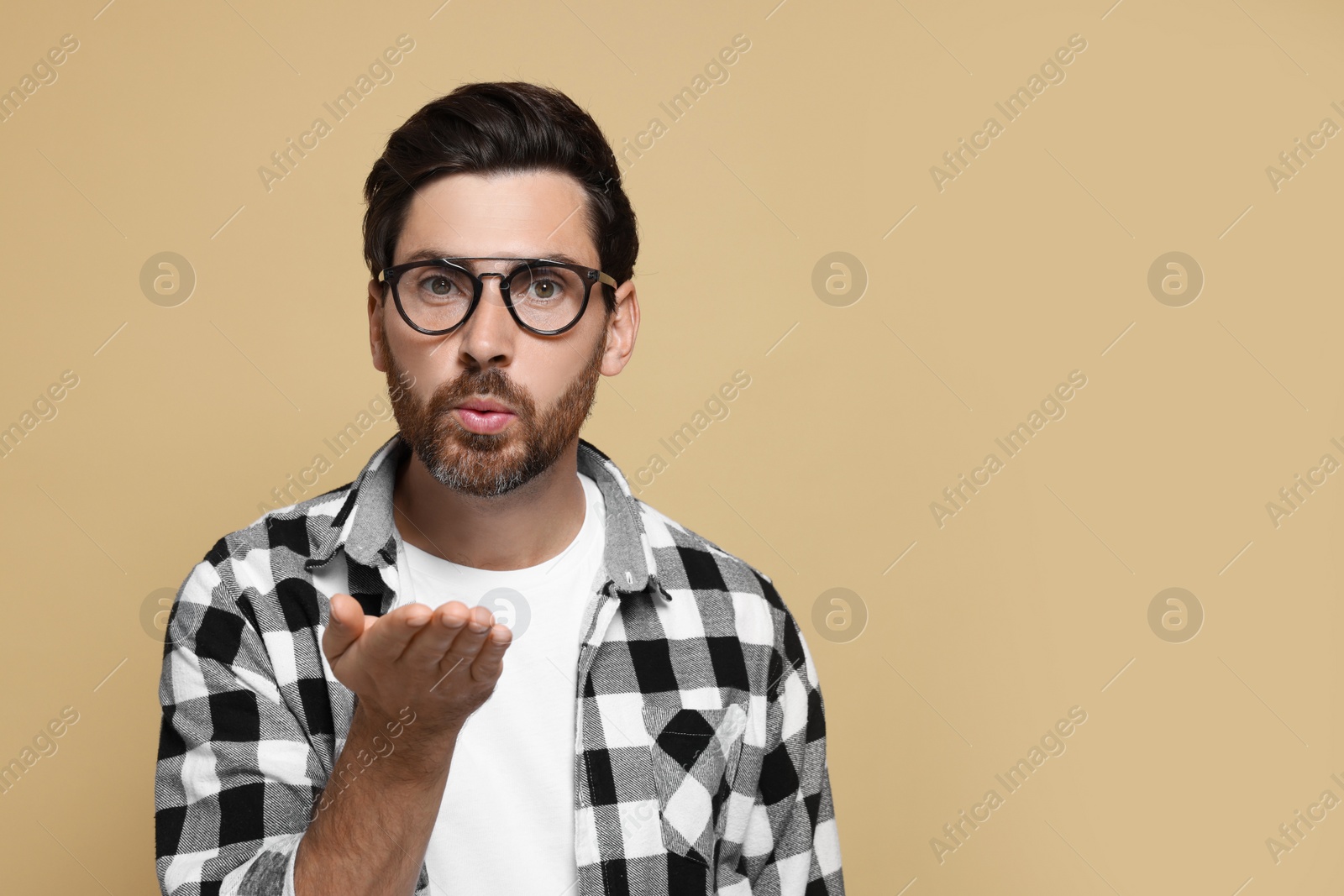 Photo of Handsome man blowing kiss on beige background. Space for text