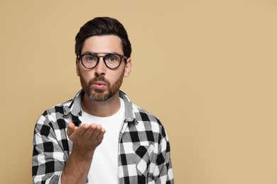 Handsome man blowing kiss on beige background. Space for text