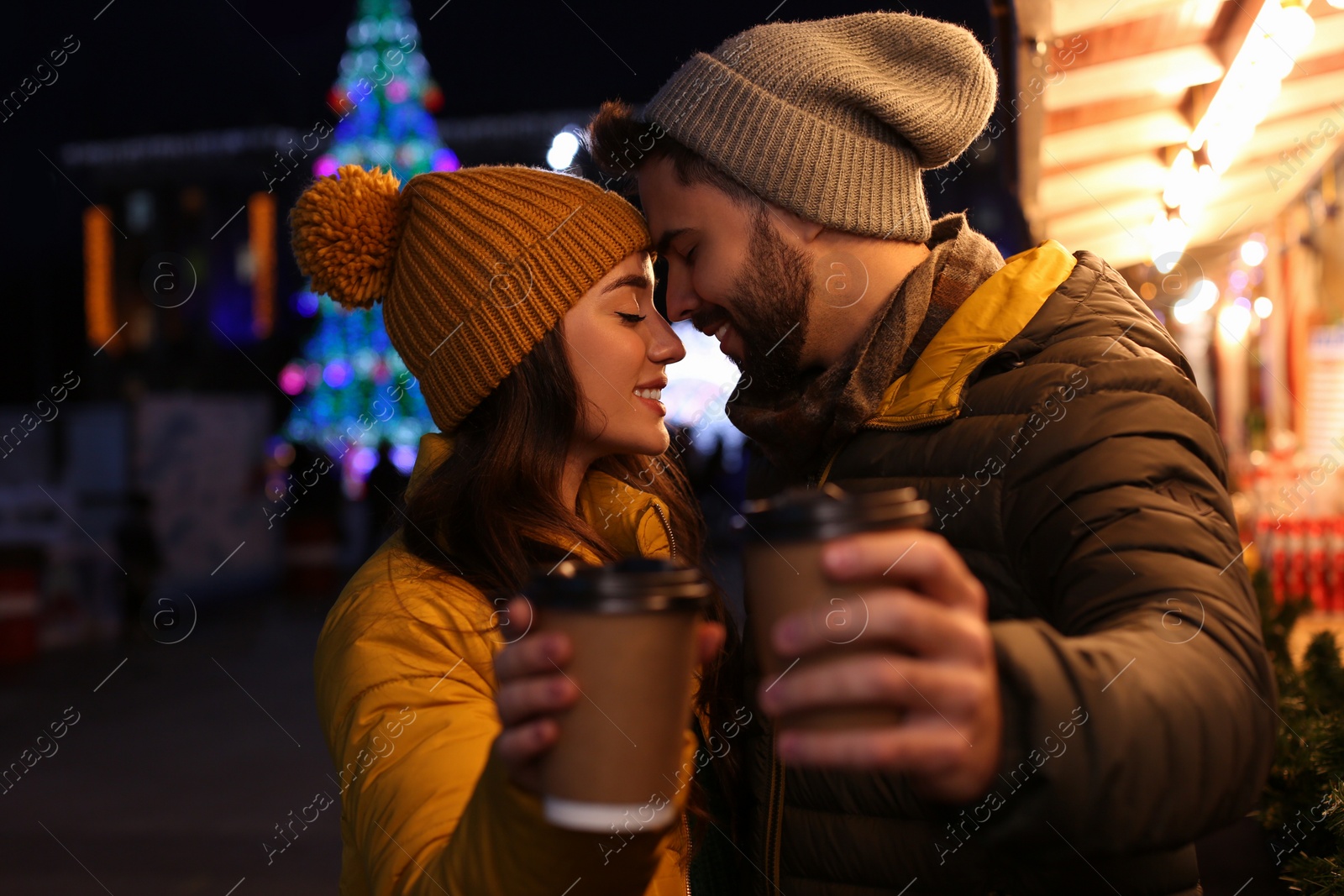 Photo of Lovely couple with cups of hot drinks spending time together at Christmas fair