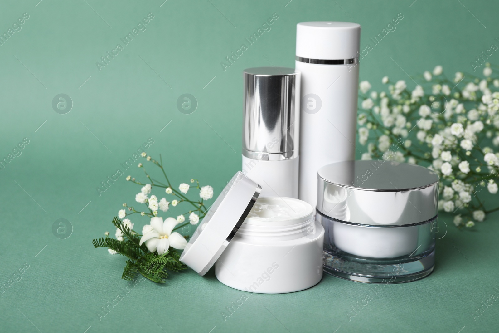 Photo of Set of luxury cosmetic products and plants on blue-green background