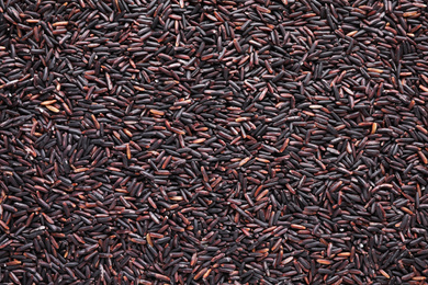 Photo of Uncooked organic brown rice as background, top view
