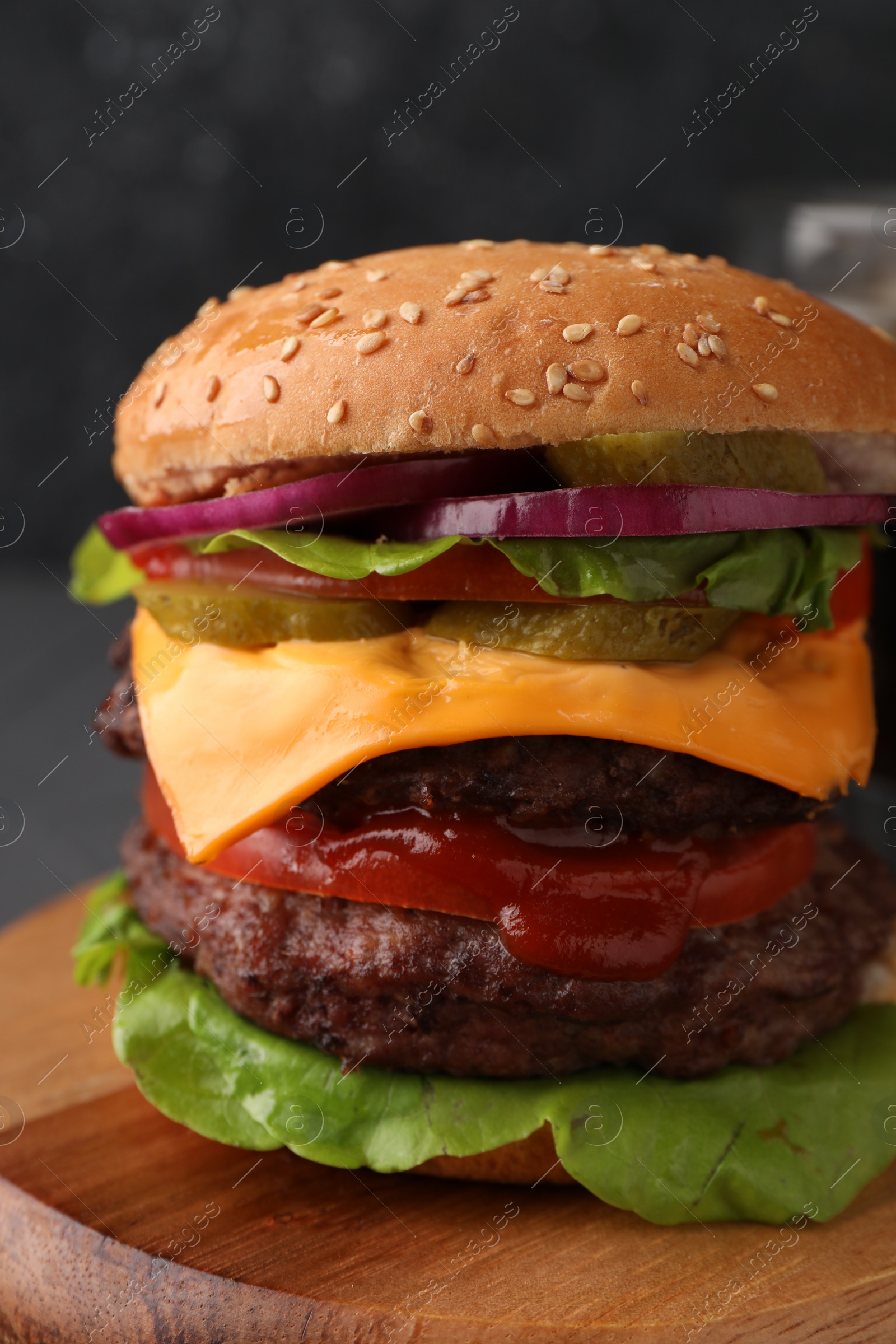 Photo of Tasty cheeseburger with patties and tomato on table, closeup