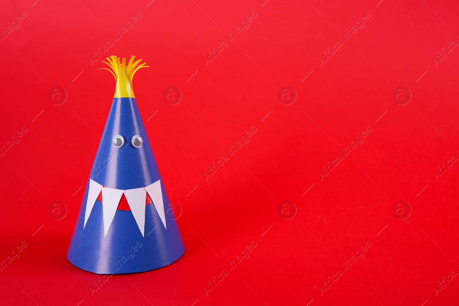 Photo of Funny blue monster on red background, space for text. Halloween decoration