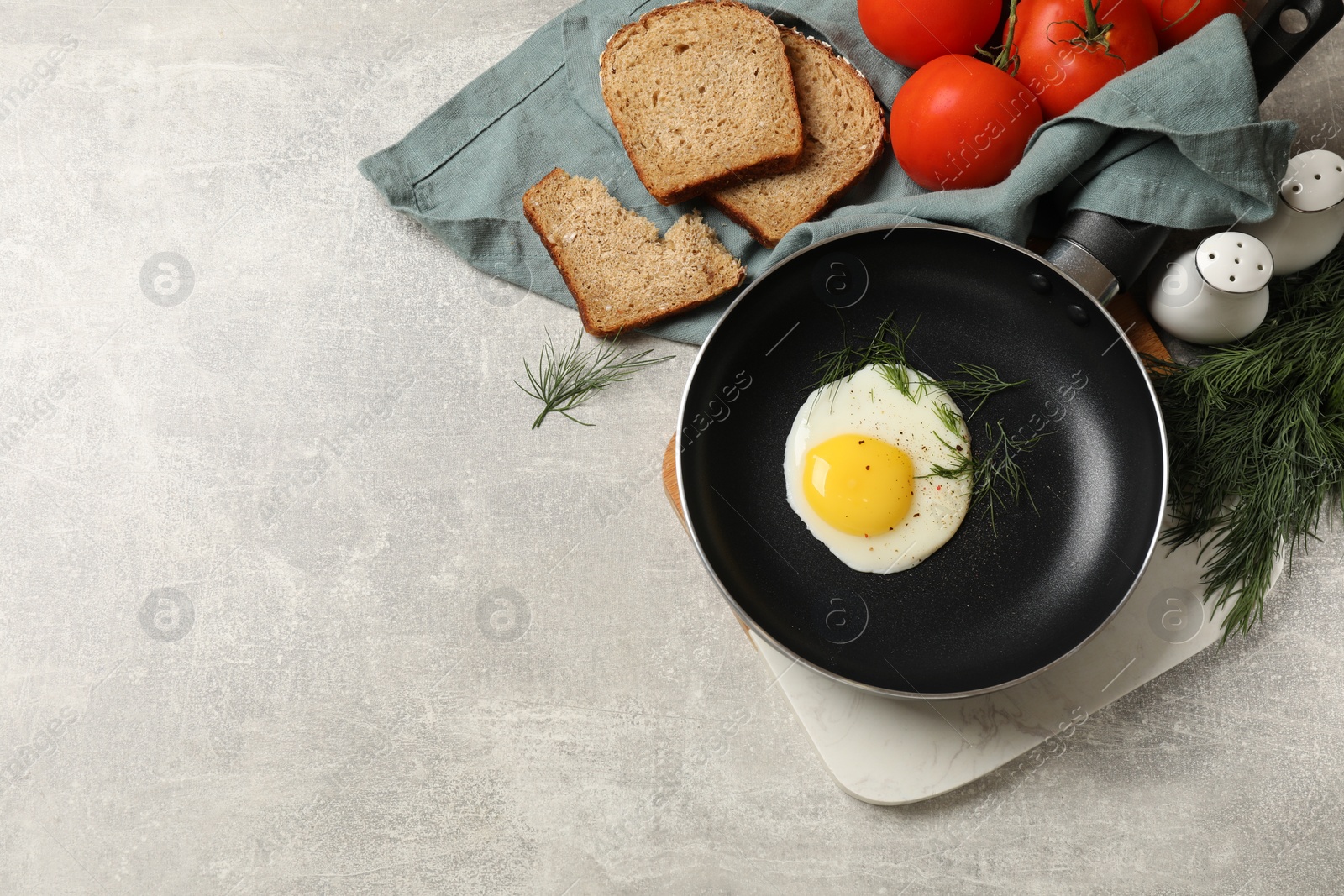 Photo of Delicious fried egg served with bread and tomatoes on grey table, flat lay. Space for text