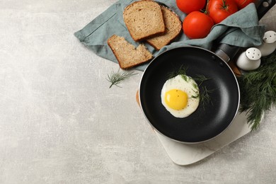 Delicious fried egg served with bread and tomatoes on grey table, flat lay. Space for text