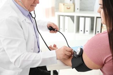 Photo of Doctor measuring blood pressure of overweight woman in clinic