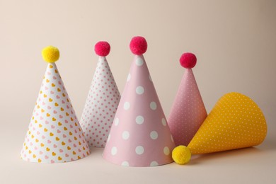 Beautiful party hats with pompoms on beige background