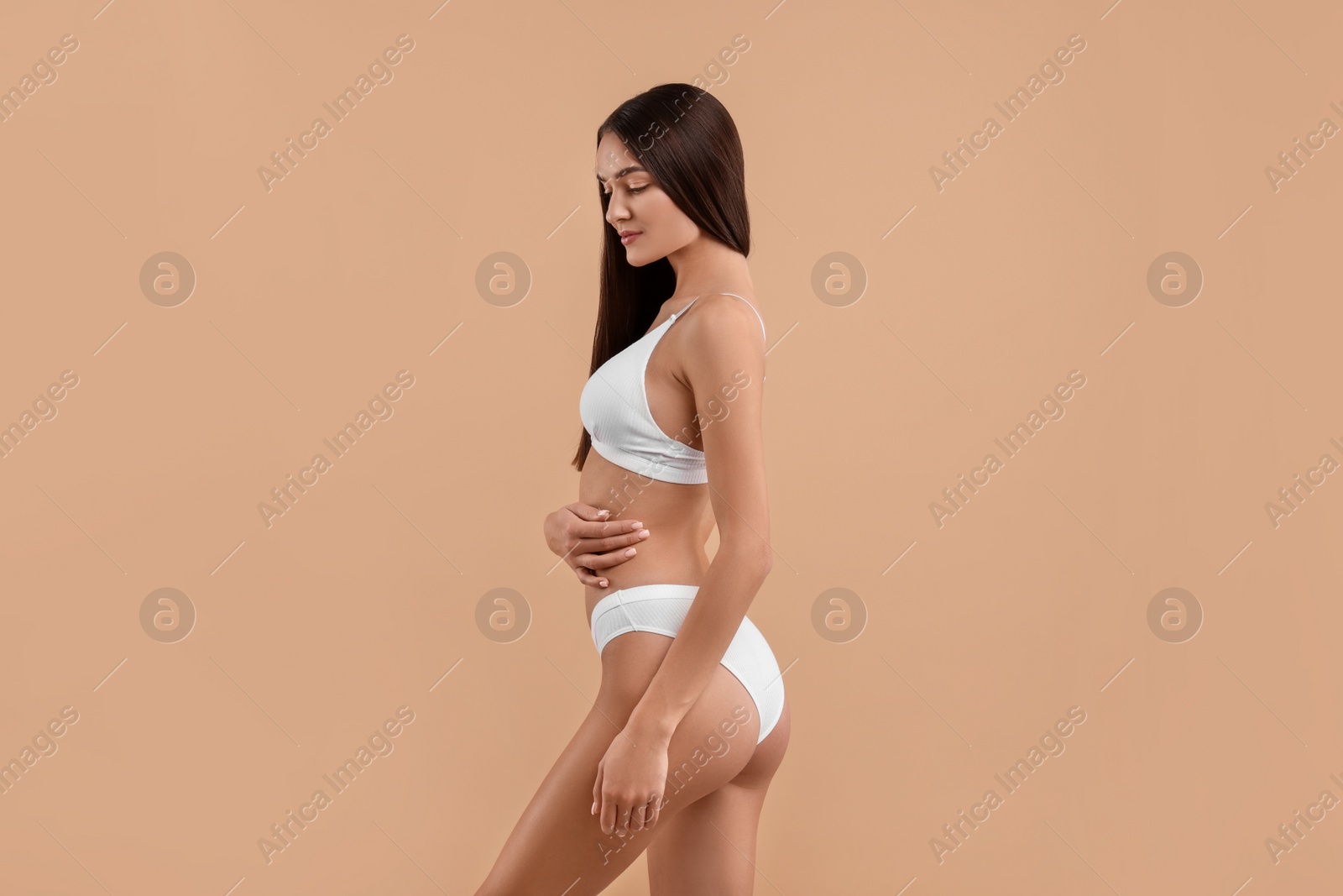 Photo of Young woman in stylish white bikini on beige background