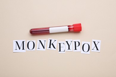 Photo of Word Monkeypox and test tube with blood sample on beige background, flat lay