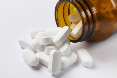 Photo of Bottle and vitamin capsules on white background, closeup