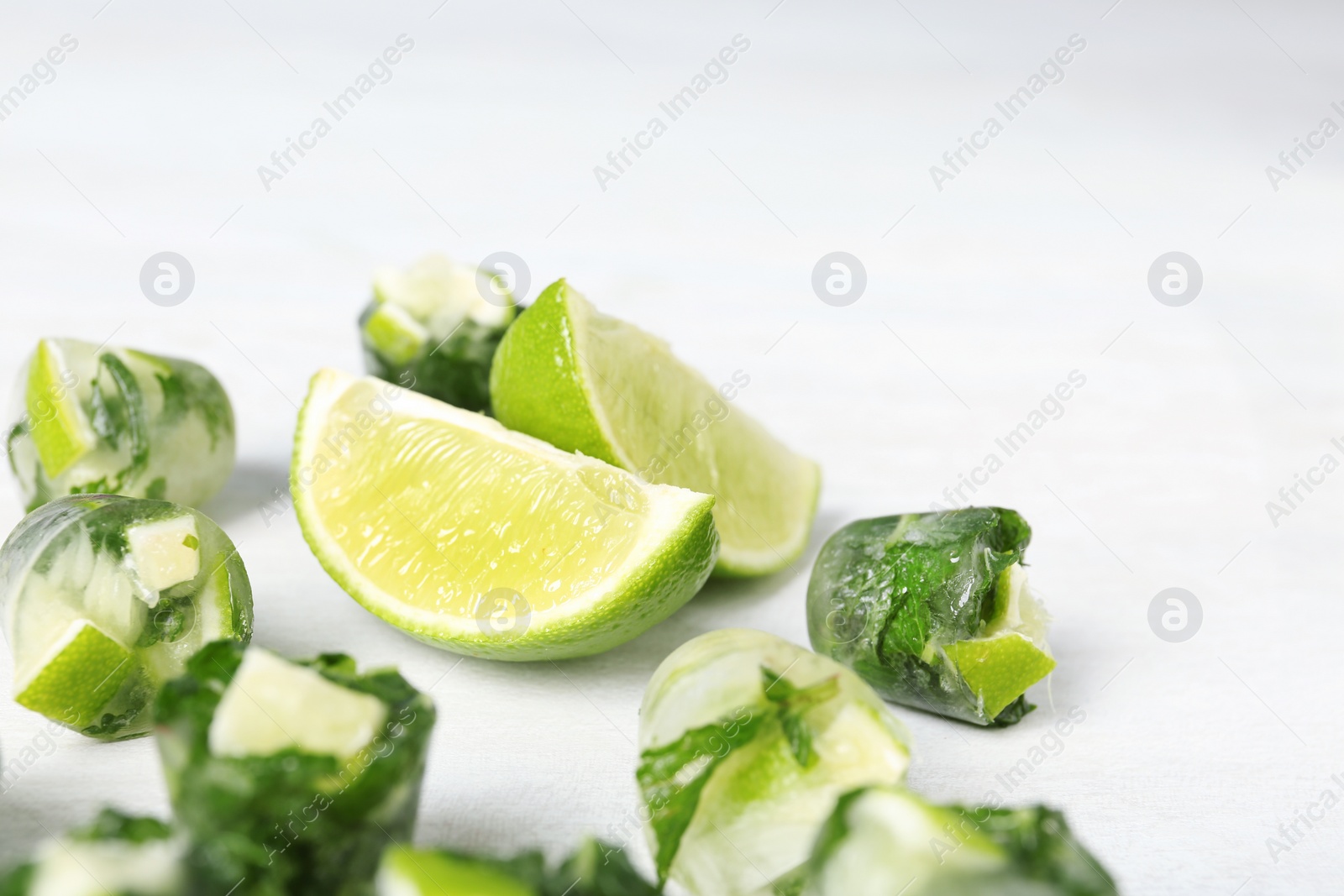 Photo of Lime and mint ice cubes with fresh fruit on light table