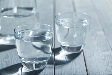Photo of Glasses of water on grey wooden table. Refreshing drink
