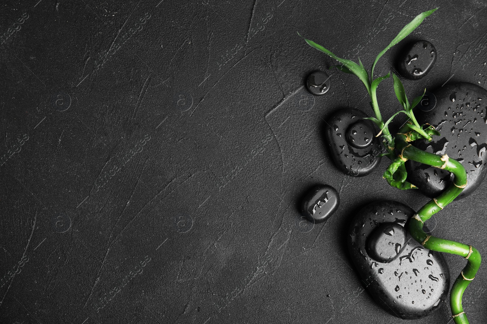 Photo of Zen stones and bamboo on dark background, top view with space for text