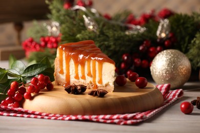 Photo of Tasty caramel cheesecake and Christmas decorations on wooden table, space for text