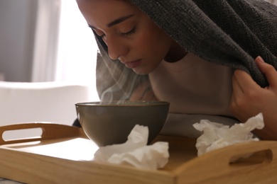 Woman with plaid doing inhalation above bowl indoors