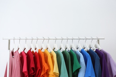 Photo of Rack with bright clothes on white background. Rainbow colors