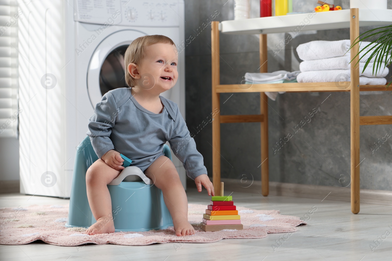 Photo of Little child sitting on plastic baby potty indoors. Space for text