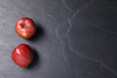 Photo of Ripe red apples on black textured table, top view. Space for text