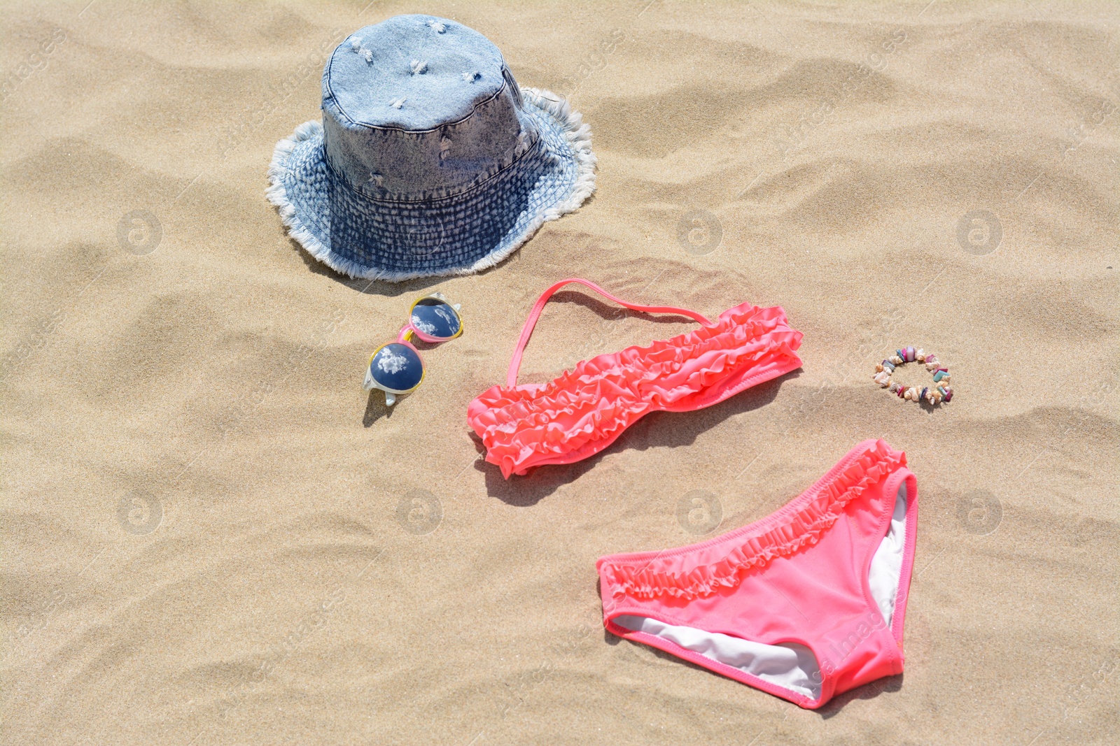 Photo of Jeans hat, sunglasses and bikini on sand. Beach accessories