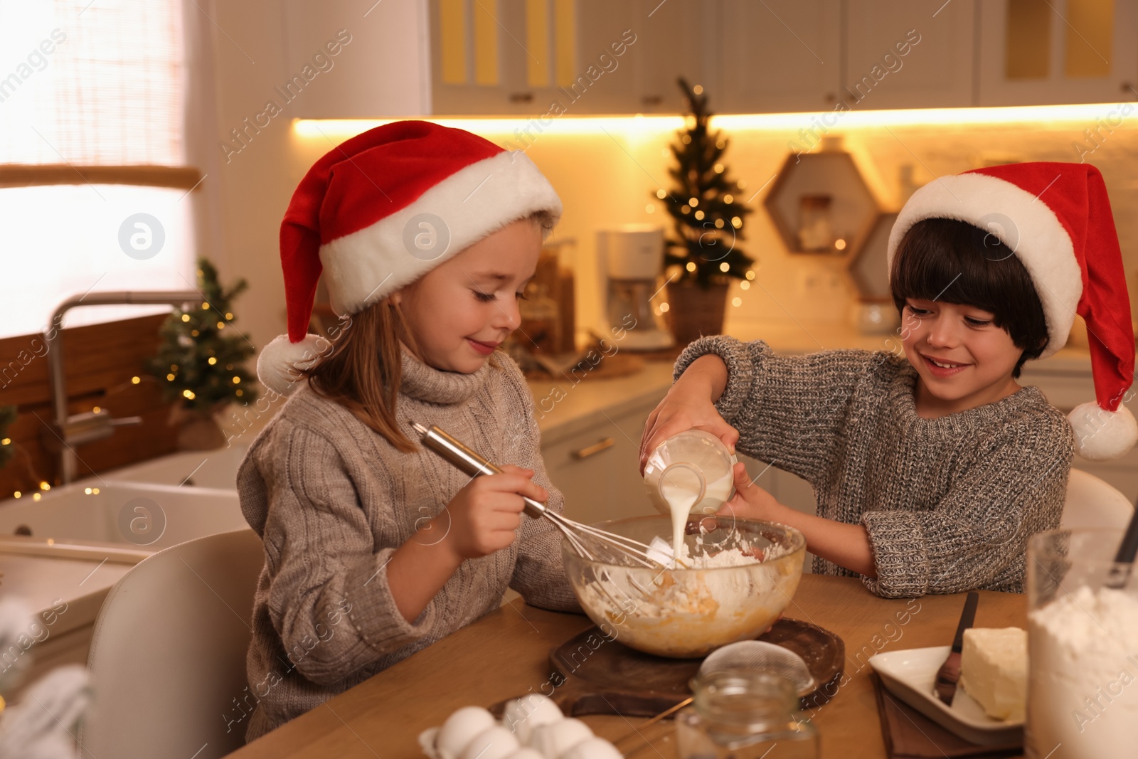 Photo of Cute little children making dough for Christmas cookies in kitchen