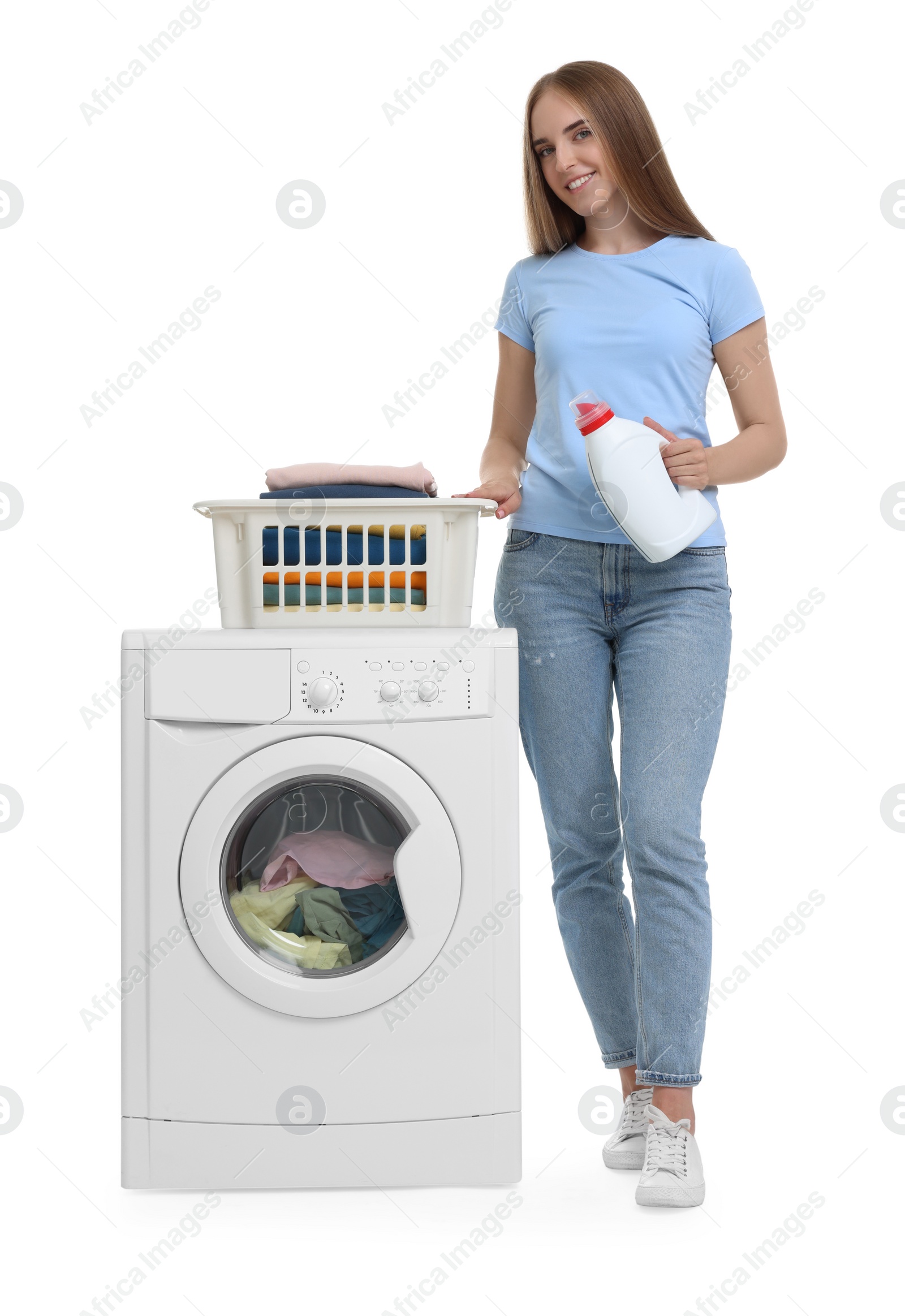 Photo of Beautiful young woman with detergent and laundry basket near washing machine on white background