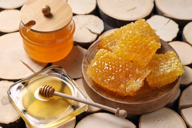 Photo of Natural honeycombs with honey and wooden dipper on textured table