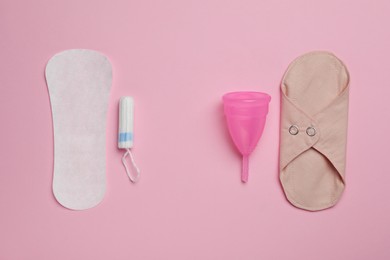Reusable and disposable menstrual hygiene products on pink background, flat lay