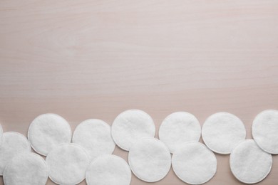 Many clean cotton pads on wooden table, flat lay. Space for text