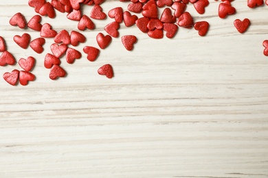 Bright heart shaped sprinkles on white wooden table, flat lay. Space for text