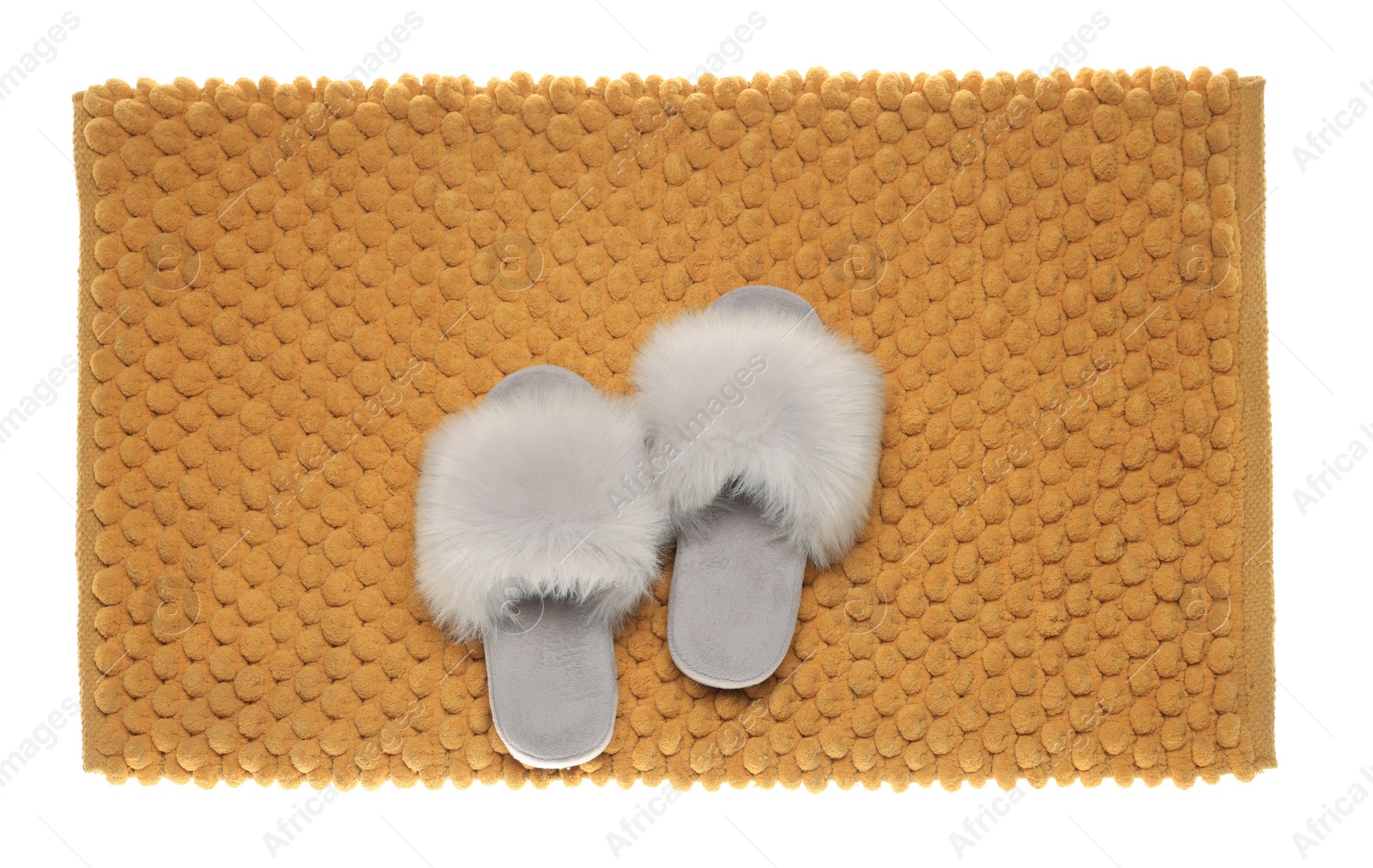 Photo of Soft orange bath mat and slippers isolated on white, top view