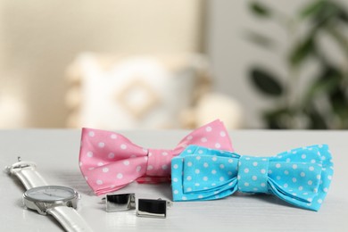 Photo of Stylish color bow ties, wristwatch and cufflinks on wooden table